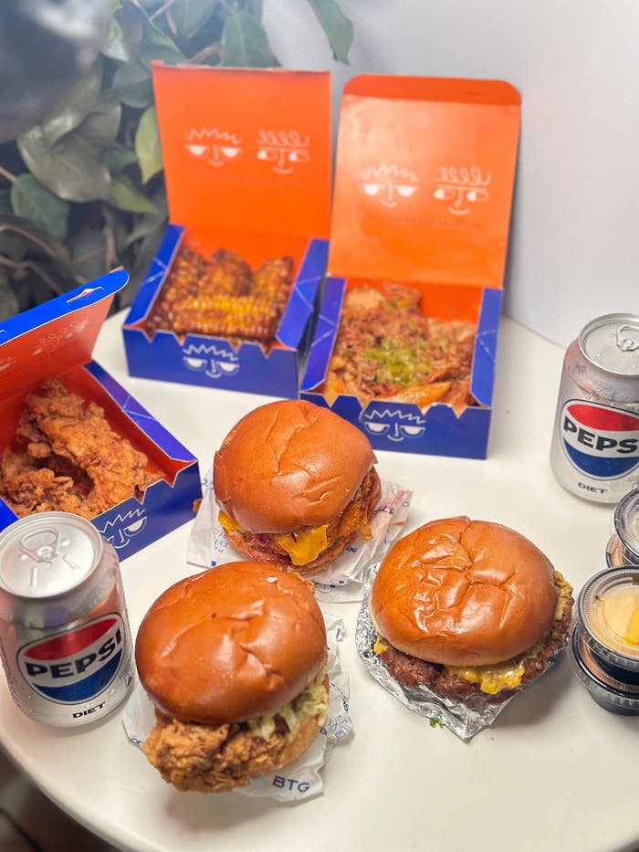 Fast food setup with burgers, fried chicken, and drinks on a table.
